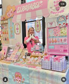 a woman standing in front of a pink and white counter top with hello kitty merchandise on it