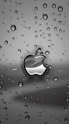 an apple logo is seen through the raindrops on a glass surface in this black and white photo