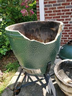 a large green pot sitting on top of a metal stand next to a brick wall