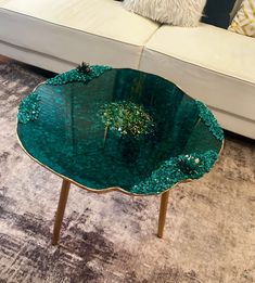 a green table sitting on top of a carpeted floor next to a white couch