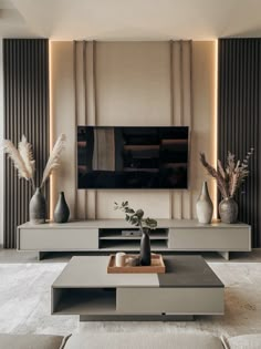 a living room with a large television and two vases on the table in front of it