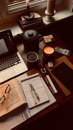 a laptop computer sitting on top of a wooden desk next to a cup of coffee