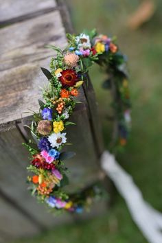 a wreath made out of flowers sitting on top of a wooden bench