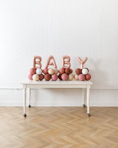 a white table topped with balloons and letters that spell out the word baby on top of it