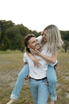 a man holding a woman in his arms while she holds her on the back and smiles