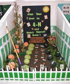 an indoor garden with plants and dirt in the center, surrounded by white picket fence