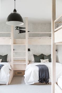 two bunk beds in a room with white walls and carpeted flooring, one has a ladder to the ceiling