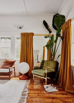 a living room filled with furniture and a large window covered in yellow curtained drapes