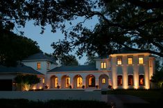 a large white house lit up at night with lights on it's front windows