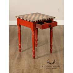 a wooden table with a checkered top and drawer on the bottom is shown in front of a white wall