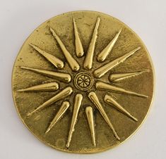 a gold colored metal object with spikes on it's center and four pointed spokes in the middle