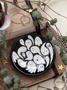 a black and white plate with ghost faces on it sitting next to some green plants