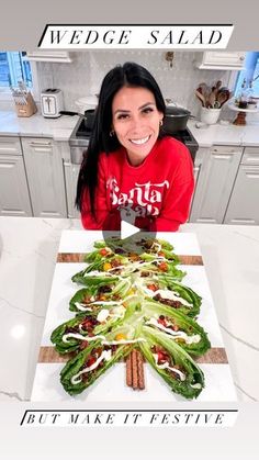 a woman sitting in front of a christmas tree made out of lettuce leaves