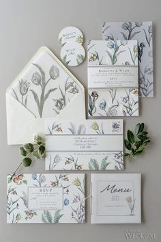 the wedding stationery is laid out on top of each other with flowers and leaves