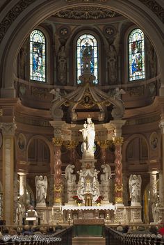 the interior of a large church with statues and stained glass windows on either side of the alter