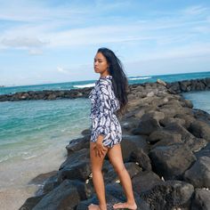 a woman standing on rocks near the ocean