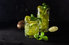 two glasses filled with lemonade and mint garnish next to an onion on a black surface