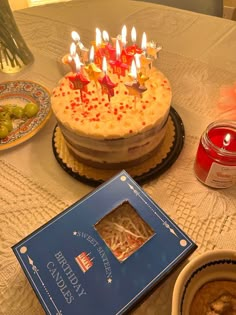 a birthday cake sitting on top of a table next to a bowl of soup and a candle