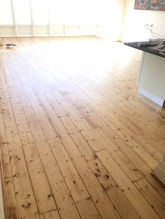 an empty kitchen with hard wood floors and white cabinets