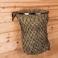 a basket that has hay in it hanging on the side of a wooden wall next to wood planks