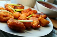 fried food on a white plate with dipping sauce in the backgroung area