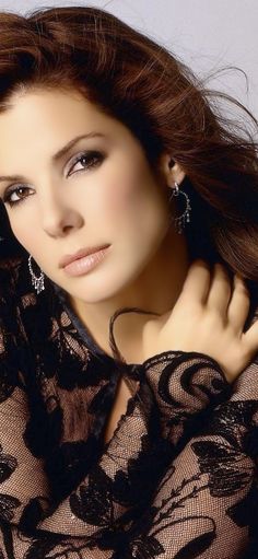 a woman with long hair and earrings on her neck posing for a photo in black lace