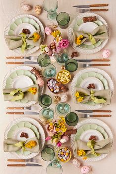 the table is set with plates, cups, and flowers on it for easter dinner