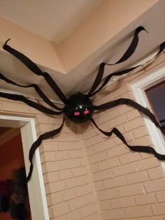 a large spider hanging from the ceiling in front of a door with it's eyes glowing