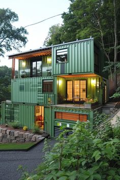 two green shipping containers are stacked on top of each other in front of some trees