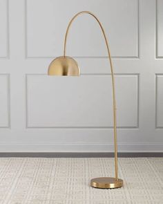 a gold floor lamp in front of a white wall with a gray carpet and door