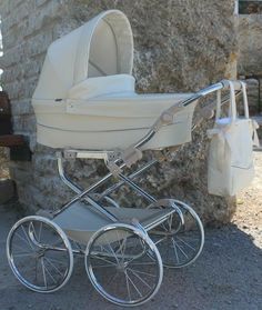 a baby stroller sitting in front of a stone wall with a handbag hanging from it