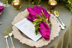 the table is set with purple napkins and silverware, along with candles and flowers