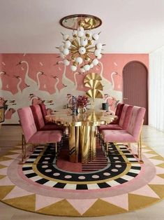 a dining room with pink chairs and a gold table surrounded by flamingo wallpaper