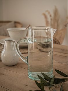 a glass pitcher filled with water sitting on top of a wooden table