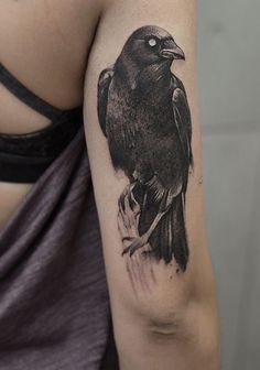 a woman's arm with a black bird tattoo on the left side of her body