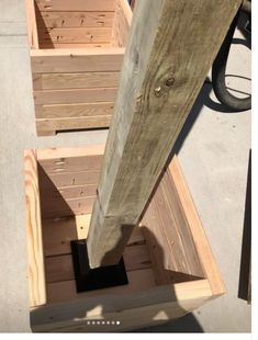 two wooden boxes sitting next to each other on top of a cement ground with a bike in the background