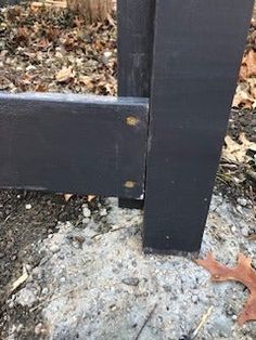 a black wooden bench sitting on top of a pile of leaves next to a tree