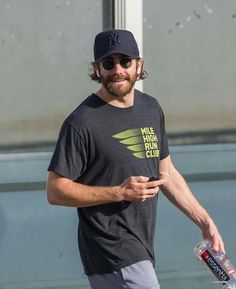 a man walking down the street with a drink in his hand and wearing a hat