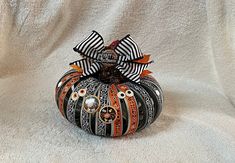 a decorative pumpkin decorated with black and orange designs on it's side sitting on a white surface