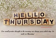 scrabbled wooden blocks spelling the word hello thursday with white flowers