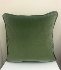 a green pillow sitting on top of a white bed