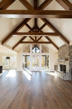 an empty living room with wood flooring and vaulted ceiling, fireplace in the center