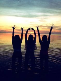 three girls standing in the water with their arms up