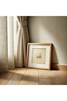 an empty picture frame sitting on the floor next to a window