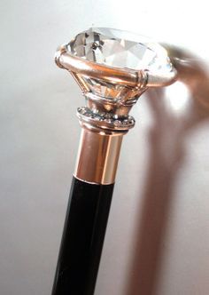 a close up view of a diamond on a black and gold pen with a white wall in the background