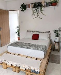 a bed made out of wooden pallets with plants on the headboard and foot board