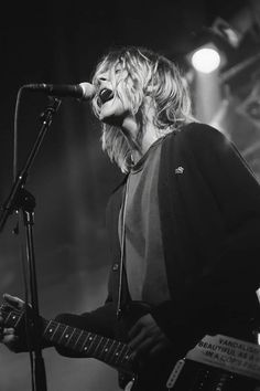 a woman singing into a microphone while holding a guitar