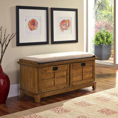 a wooden bench with two pictures on the wall above it and a red vase next to it