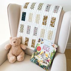 a teddy bear sitting in a chair next to a book on the arm of a chair