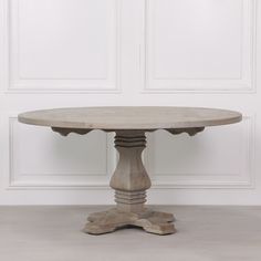 a round table with two pedestals on the top and one at the base, against a white wall